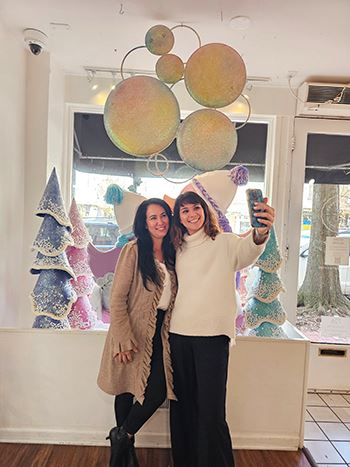 Two women standing beside each other taking selfie in store